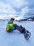 man with snowboard sitting at snowed hill