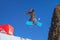 Man snowboarder flies from a jump on blue sky background