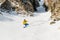 A man a snowboarder freerider descends a backcountry at high speed from a slope