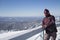 A man in snowboarding gear on the top of a mountain. Young man standing with a snowboard on the top of the mountains