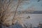 A man on a snowmobile rides a frozen river against a background of a blurry winter snowy rural landscape