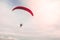 A man soaring into the sky with paramotor extreme sport adventure in summer day time with a clear sky background.