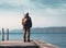 Man in solitude fishing on a wooden pier, overlooking a calm lake during twilight.