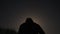 Man solo tourist with backpack climbs mountain as silhouette against full moon
