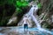 Man solo traveler adventurer standing from the back at a blue waterfall in the jungle