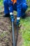 A man in special clothes puts a long black pipe for the water supply