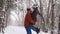 Man spinning or turning happy girlfriend holding her in his hands on snowfall in pine forest. Loving couple have fun in