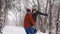 Man spinning or turning happy girlfriend holding her in his hands on snowfall in pine forest. Loving couple have fun in