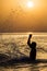 Man splashing water during summer sunset holidays. Young attractive man having fun on a tropical beach at sunset