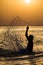 Man splashing water during summer sunset holidays. Young attractive man having fun on a tropical beach at sunset