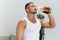 Man sports drinking water during break from workout, pumped up man fitness trainer works out at home, the concept of