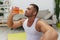 Man sports drinking water during break from workout, pumped up man fitness trainer works out at home, the concept of