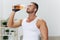 Man sports drinking water during break from workout, pumped up man fitness trainer works out at home, the concept of