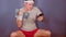 Man in sports headband lifting dumbbell, browsing mobile phone and sitting on gymnastic ball. Active male doing sport