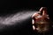 Man spraying luxury perfume on black background, closeup