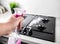 A man sprays a cleaning agent on a gas stove in the kitchen. Cleaning from dirt and grease, caring for a gas hob. Copy