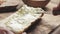 Man spread cream cheese with herbs over baguette in slow motion