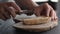 Man spreading chocolate hazelnut butter on ciabatta slice on olive board