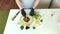 A man spreads tomato paste on a pizza base. Cooking ingredients are laid out nearby. Making pizza at home