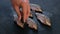 Man sprinkles salt and pepper on freshly brushed carp on a black table. Cooking fish. Hand close-up.