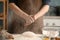 Man sprinkling flour over dough on table