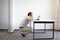 Man squatting at the desk, working with tablet