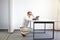 Man squatting at the desk, working with tablet