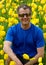 A man squatting down in front of a yellow tulips gardrn