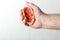 Man squeezed grapefruit juice. Squeezed grapefruit in male hand against white wall