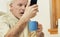 Man squints at phone, breakfasting in kitchen