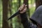 A man stabs with a large knife from above in the forest, close-up, selective focus. The concept: an attack on passers-by, a rapist