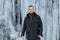 Man standing against cliff full of icicles