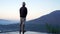 Man standing alone from behind on the edge of the pool at sunrise with water reflection and blue mount Batur view background.