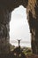 Man standing alone in cave Travel adventure vacations happy raised hands