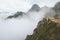 Man standing alone on mountain cliff edge foggy nature travel active healthy lifestyle