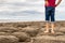 Man standing barefoot on the beach of stones on the seashore