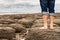 Man standing barefoot on the beach of stones on the seashore