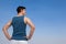 Man standing on beach with hand on hips against blue sky