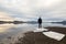 Man standing at the beach, ice floes on dark sand, calm sea, mist and fog. Hamresanden, Kristiansand, Norway