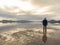 Man standing at the beach, reflections of the man in the water. Calm sea, mist and fog. Hamresanden, Kristiansand