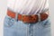 Man standing in blue jeans and brown leather handmade belt