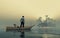 Man standing in a boat looking at a far island, during sunset at lake .