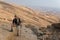 Man standing desert mountain slope.