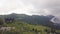 Man standing on edge of mountain peak on background green valley drone view