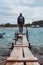 man standing at edge of the small fishing pier looking at stormy sea