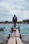 man standing at edge of the small fishing pier looking at stormy sea