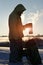 Man standing at the field in winter. He is going to drink hot coffee outside. Backlighting. Closeup. Silhouette