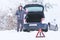 Man standing in front of damaged car holding bottle of antifreeze coolantin.