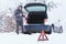 Man standing in front of damaged car holding bottle of antifreeze coolantin.