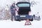 Man standing in front of damaged car holding bottle of antifreeze coolantin.